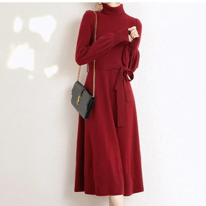Adult lady wearing a solid colour knitted turtleneck dress with long sleeves, a loose mid-length skirt, and an elastic waist.