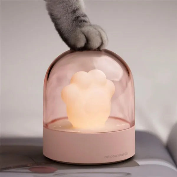 Grey or pink cat paw shaped USB rechargeable night light with music box on a desk.