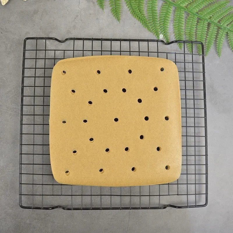 Stack of oiled paper square baking sheets with holes for air fryer use natural colour 20cm