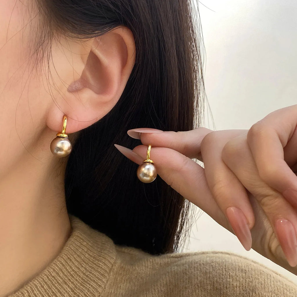 Vintage champagne pearl clip-on earrings with copper electroplated geometric design, on display as a pair