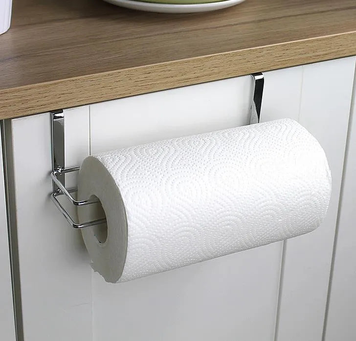 Silver stainless steel paper towel rack hanging on a wooden cabinet door.