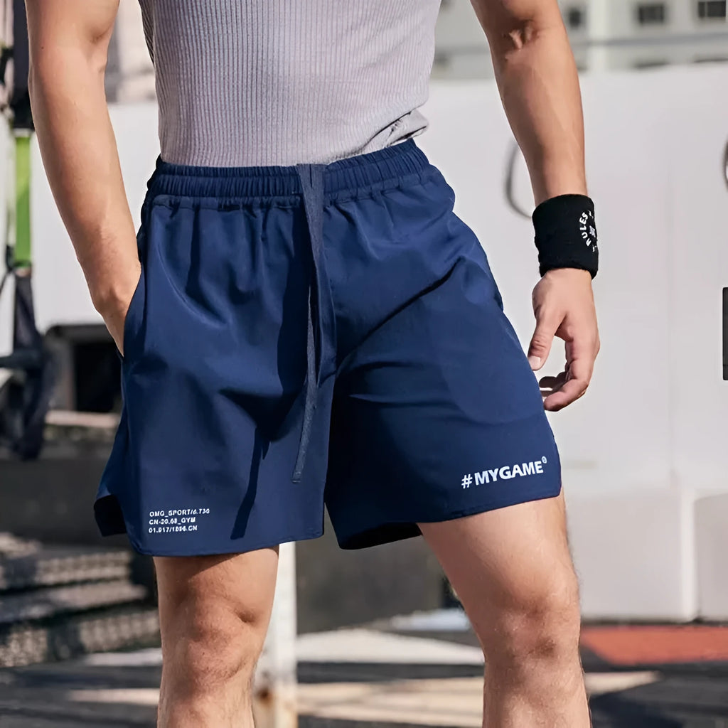 Men's grey fitness training shorts with four-point design on a gym floor