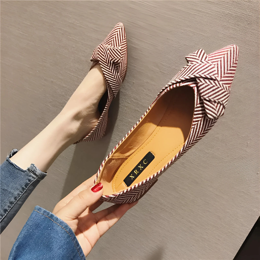 Women's pointed toe ballet flats in red and black, showing shallow mouth and low flat heel design on a plain background.