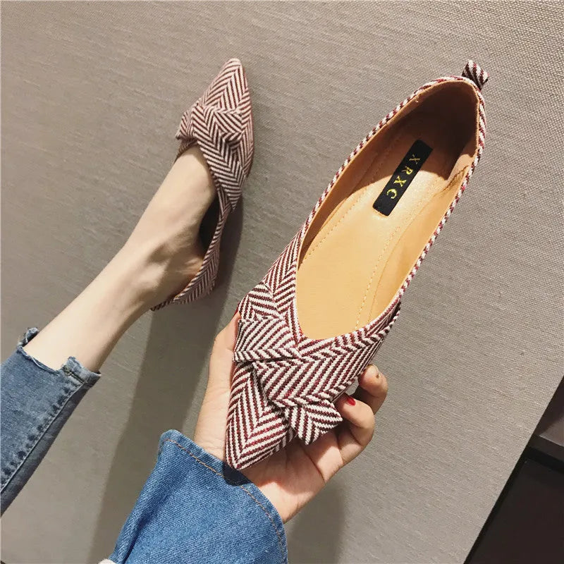 Women's pointed toe ballet flats in red and black, showing shallow mouth and low flat heel design on a plain background.