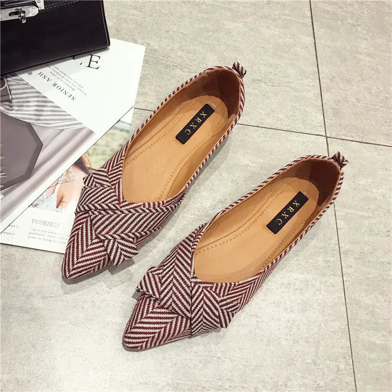 Women's pointed toe ballet flats in red and black, showing shallow mouth and low flat heel design on a plain background.