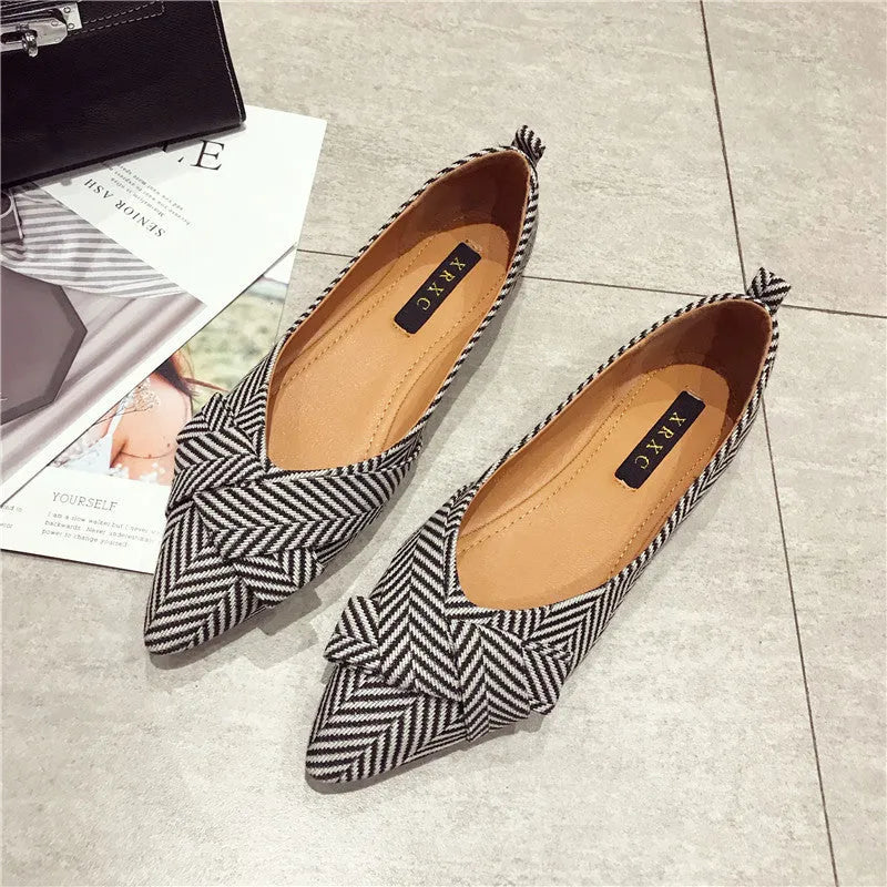 Women's pointed toe ballet flats in red and black, showing shallow mouth and low flat heel design on a plain background.