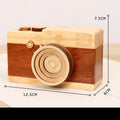 Pine wood music box with rotating camera figurine on top, shown next to its mini carton packaging.