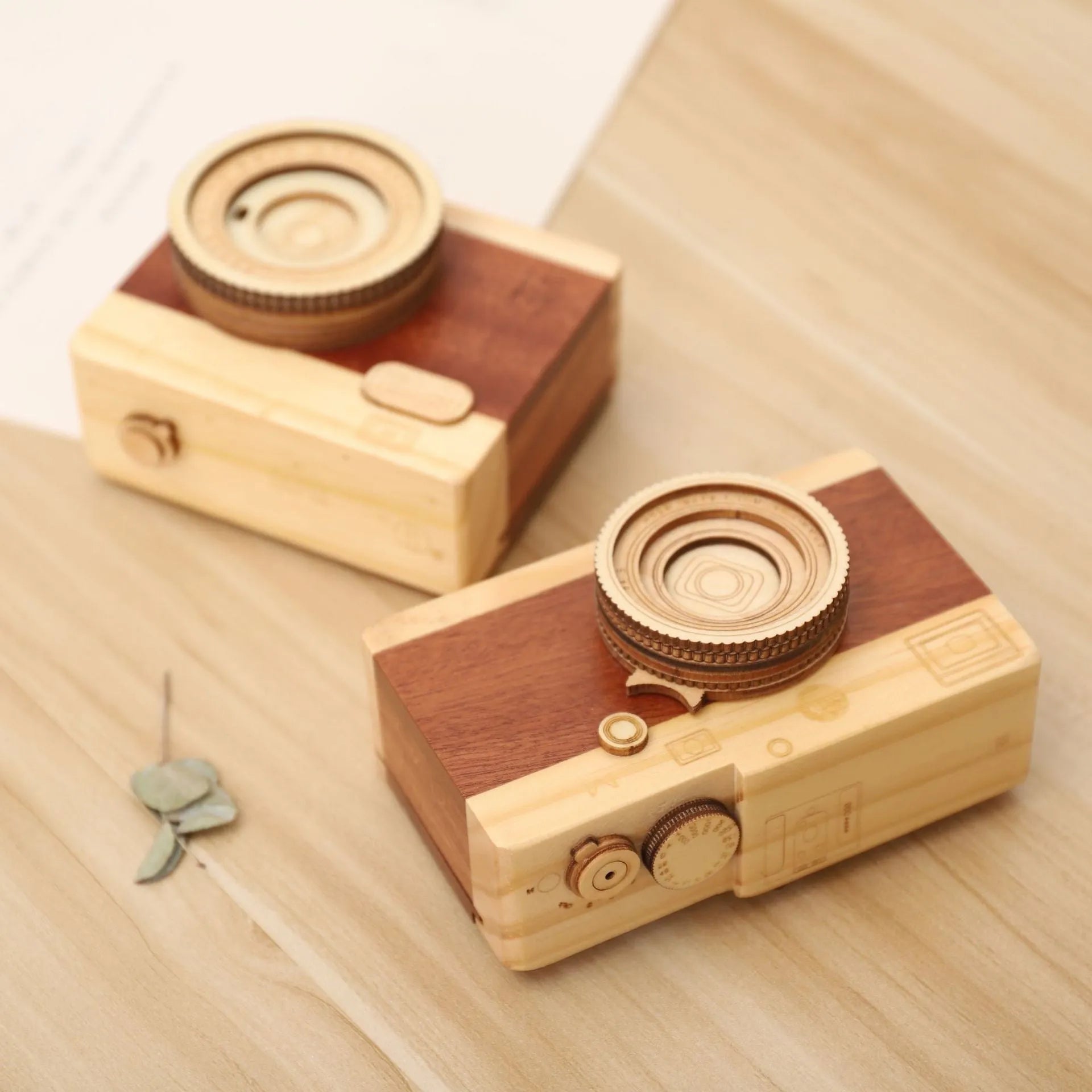 Pine wood music box with rotating camera figurine on top, shown next to its mini carton packaging.