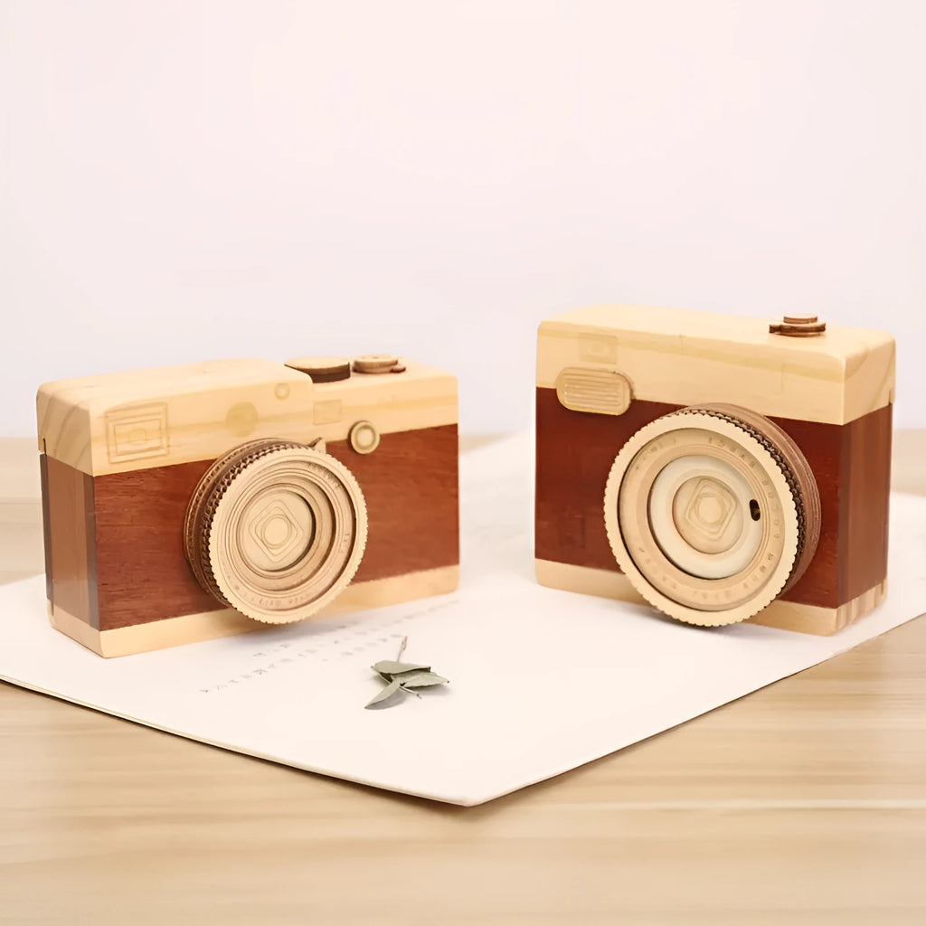 Pine wood music box with rotating camera figurine on top, shown next to its mini carton packaging.