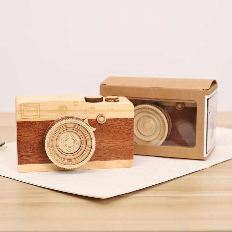 Pine wood music box with rotating camera figurine on top, shown next to its mini carton packaging.