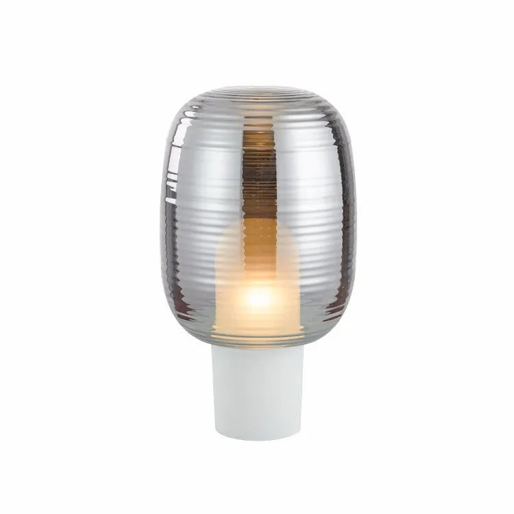 Modern glass table lamp in Cognac colour with a simple design and push button switch on a wooden table.