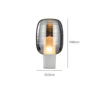 Modern glass table lamp in Cognac colour with a simple design and push button switch on a wooden table.