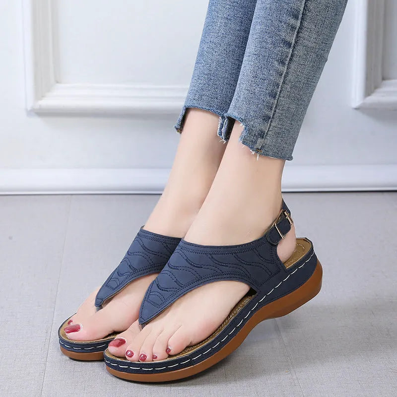 Women's black wedge heel sandals with an adjustable buckle strap on a light background.