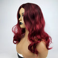 Burgundy long curly wig with gradient colour and centre bangs on a wig stand