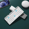 Silver white folding Bluetooth keyboard open beside smartphone showing aluminium stand