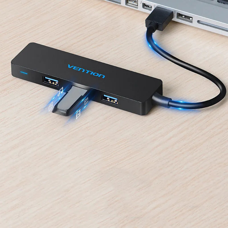Black four-port USB 3.0 hub with a short cable and nickel-plated connectors on a desk.
