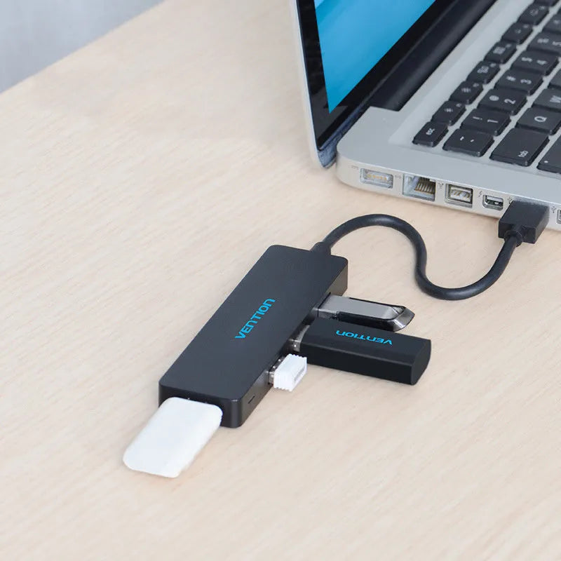 Black four-port USB 3.0 hub with a short 15cm cable on a desk.