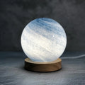 Nordic style USB-powered bedside table lamp with a coloured glass shade on a wooden table.
