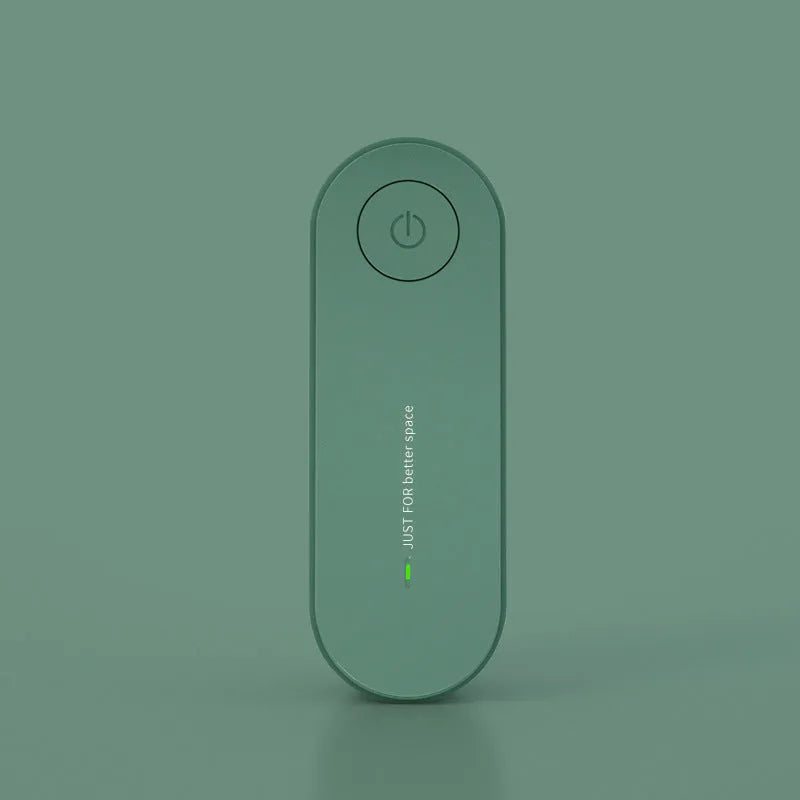 Small negative ion air purifier in black, plugged into a wall socket, with a room in the background