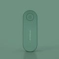 Small negative ion air purifier in black, plugged into a wall socket, with a room in the background