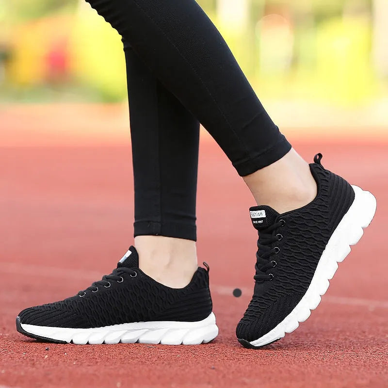 Women's running shoes with fly weave upper in black, pink, or white on a wear-resistant outsole.
