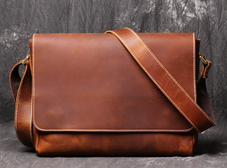 Vintage brown leather mens messenger bag with a shoulder strap, shown open to reveal internal organiser pockets.