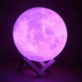 3D printed white moon lamp on a wooden stand with a glowing yellow light.
