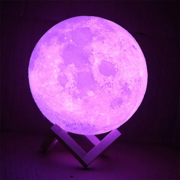 3D printed white moon lamp on a wooden stand with a glowing yellow light.
