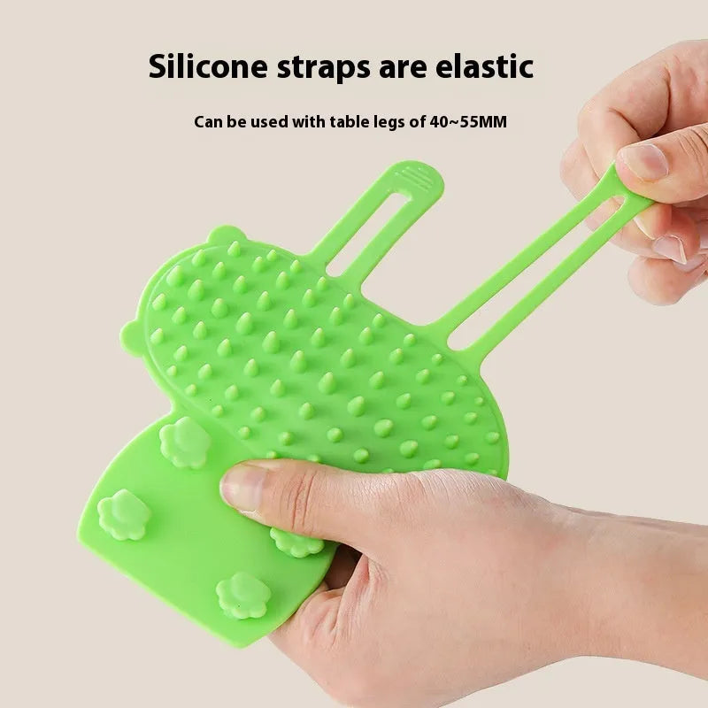Silicone cat grooming comb with adjustable strap mounted on a table leg