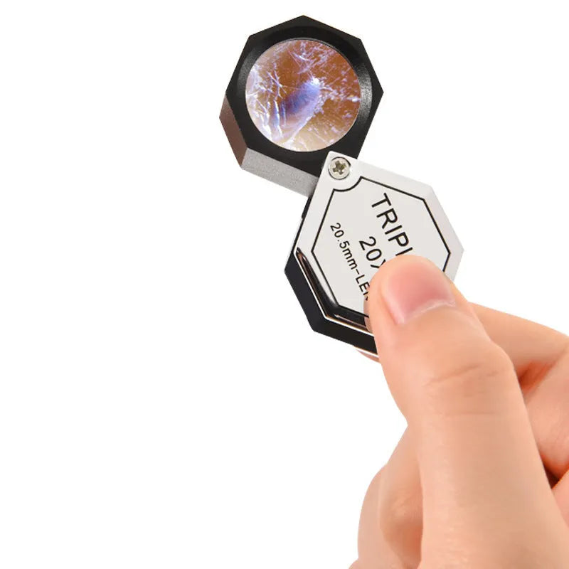Handheld portable magnifying glass with metal body for jewellery and coin identification.