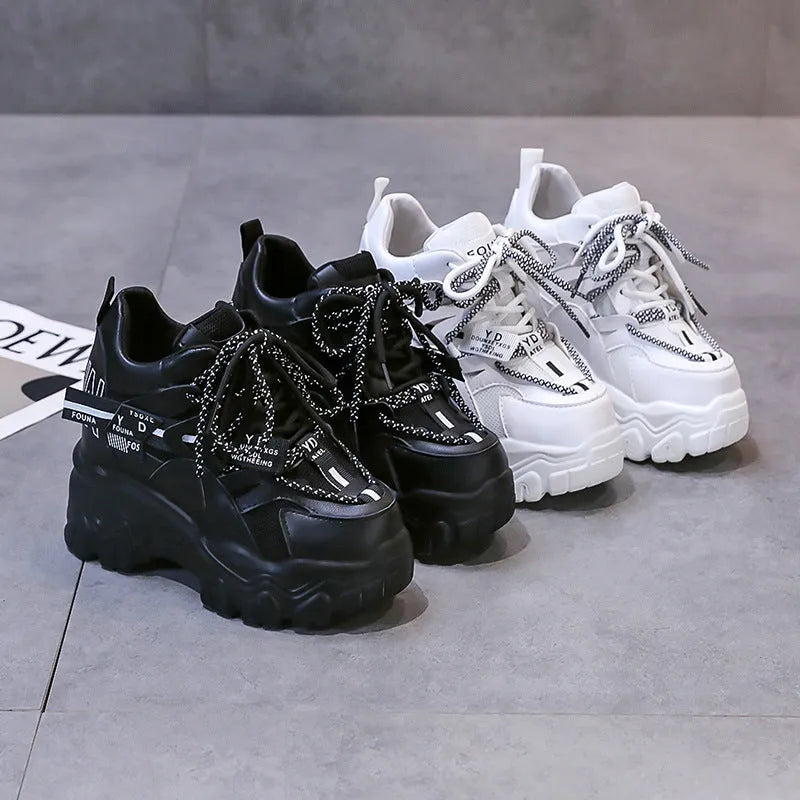 White and black women's low-top platform sports shoes with cross-strap and mesh design on a rubber sole.