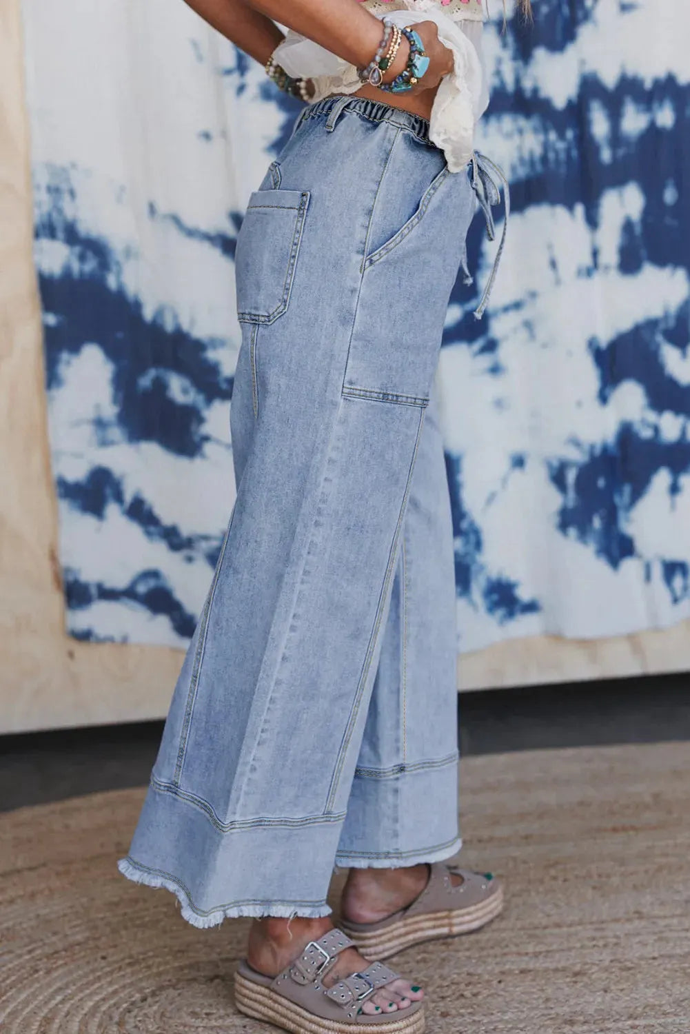 Beau Blue wide leg denim trousers with drawstring waist and raw hem finish laid flat