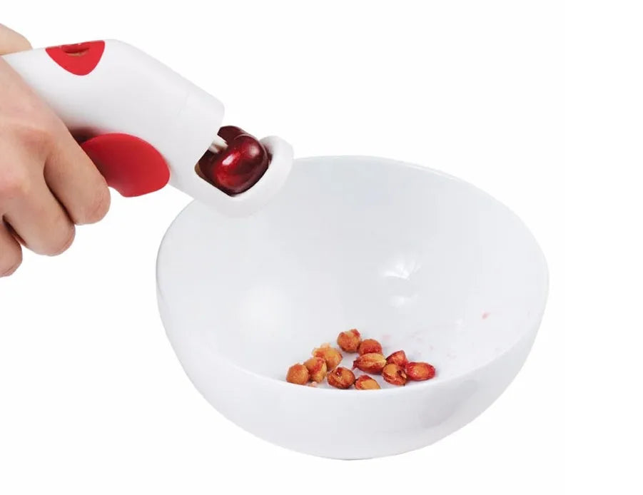 Cherry kernel remover, a handheld plastic kitchen gadget for pitting cherries, on a light background
