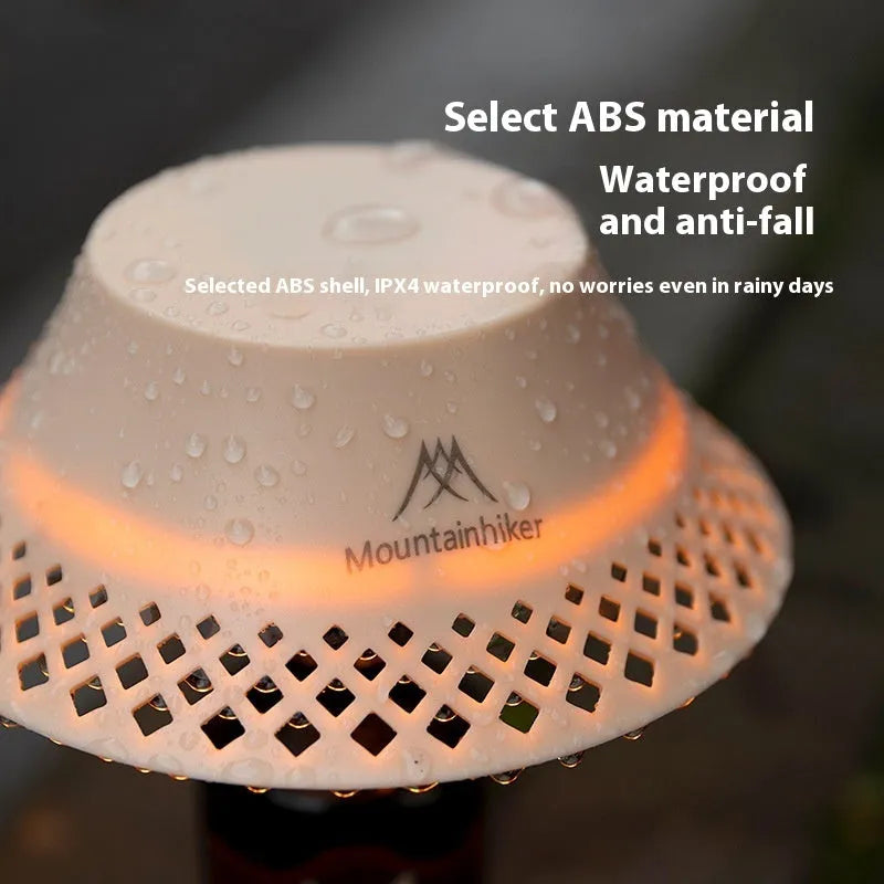 Beige wine bottle shaped camping lantern with USB-C port, shown lit on a wooden table outdoors.