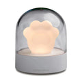Grey or pink cat paw shaped USB rechargeable night light with music box on a desk.