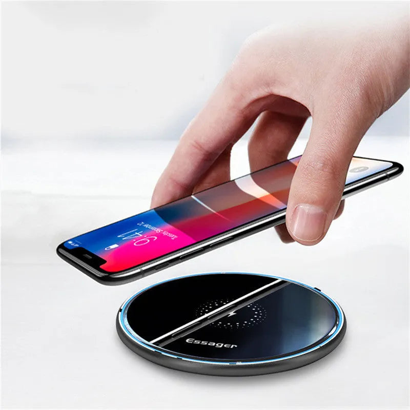 Black 15W Qi wireless charging pad on a wooden surface showing blue LED charging light