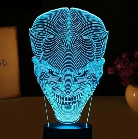 A 3D acrylic LED table lamp with a remote control on a desk, showing its colourful gradient light mode.