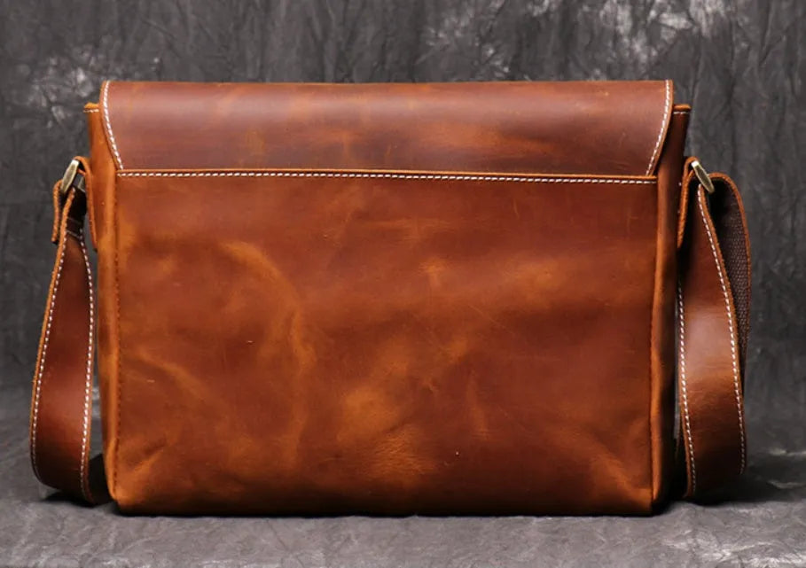 Vintage brown leather mens messenger bag with a shoulder strap, shown open to reveal internal organiser pockets.