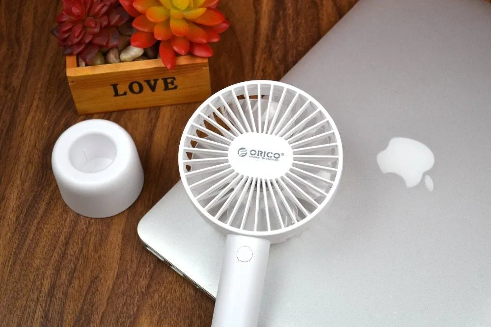 White ORICO FH1 handheld USB rechargeable small fan with three-speed buttons on a desktop.