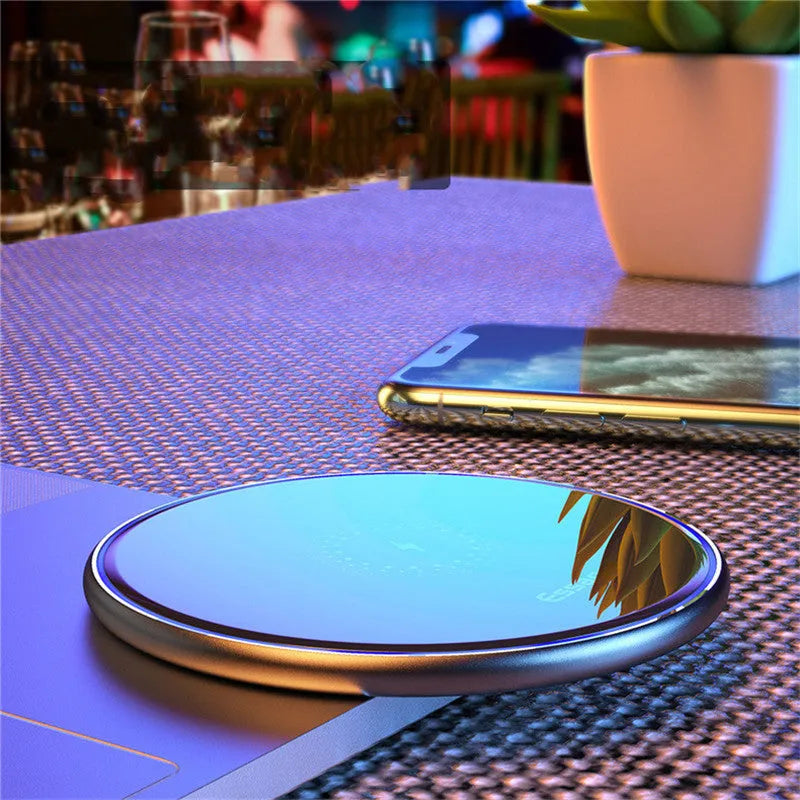 Black 15W Qi wireless charging pad on a wooden surface showing blue LED charging light