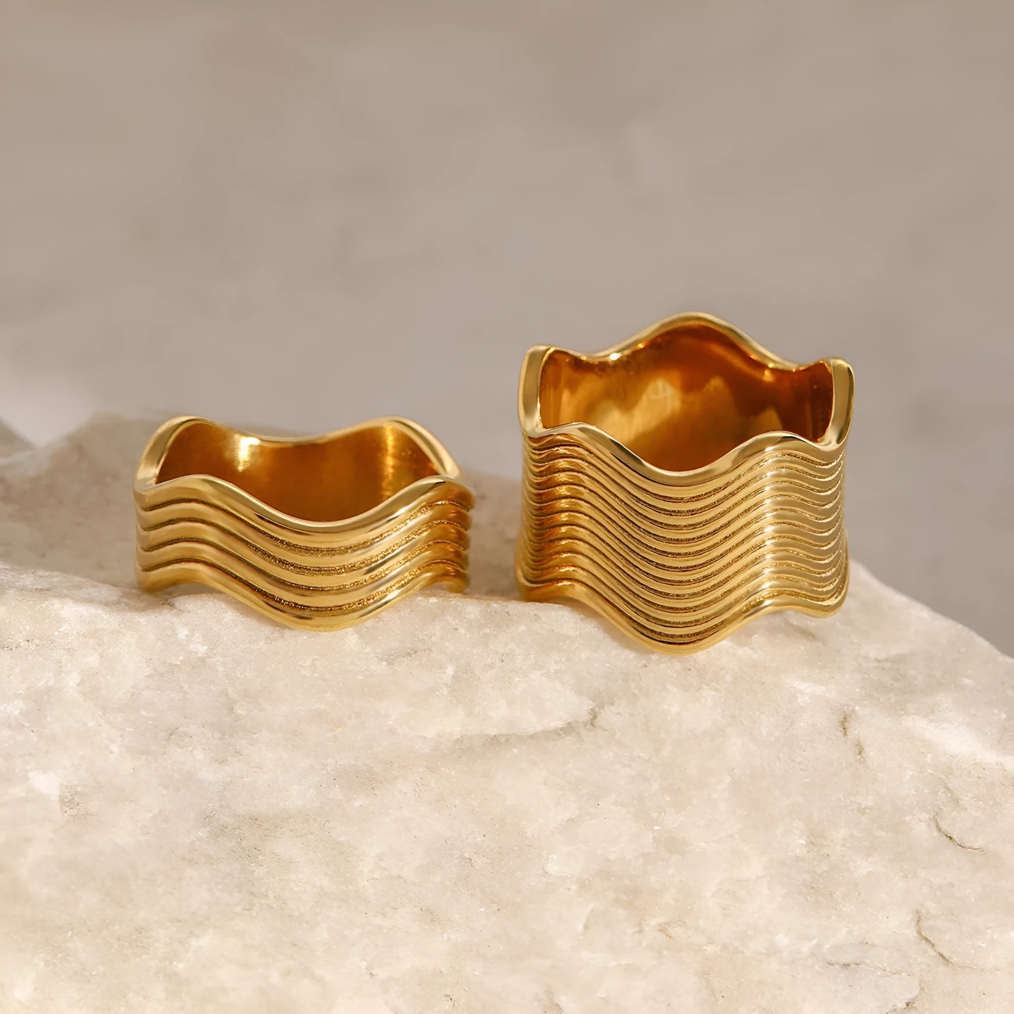 Stainless steel geometric wave pattern ring on a hand, showcasing its wide band and electroplated finish.