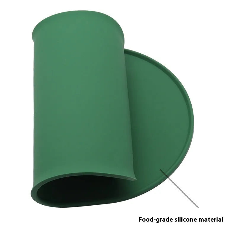 Green silicone waterproof placemat for cat bowls on a wooden floor.