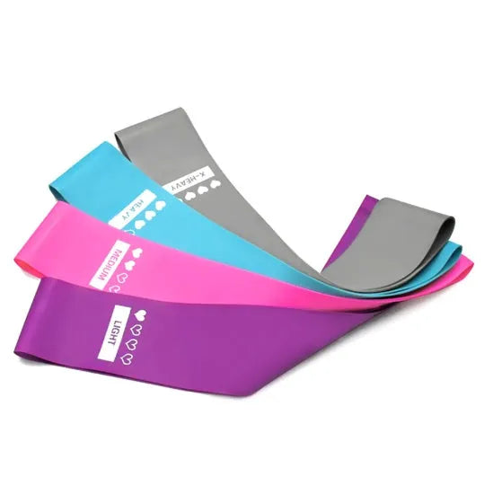Four colour-coded resistance bands in purple, pink, blue, and grey with non-slip inner lines laid flat on a surface