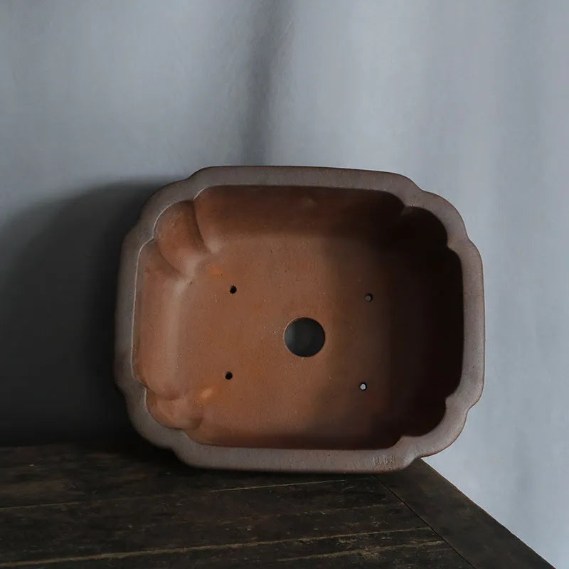 A modern rectangular flower pot made from purple sand ceramic, standing on a floor.