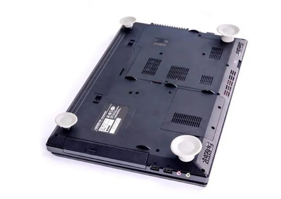 Grey durable plastic laptop cooling pads, two large and two small, on a desk next to a notebook