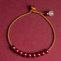 Hand-woven cinnabar and Hetian jade geometric bracelet on display