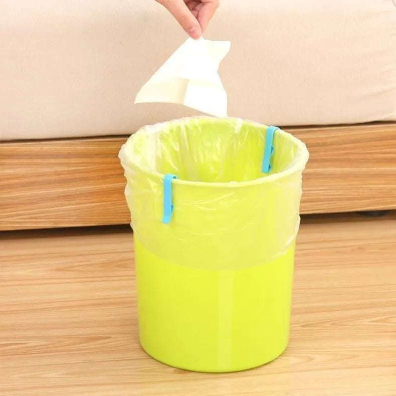 A white polypropylene garbage bag fixing clip holding a black bin liner to the rim of a metal trash can.