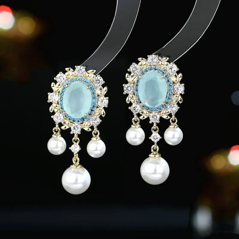 Oval geometric copper drop earrings with inlaid zircon stones, pearl details, and a tassel.