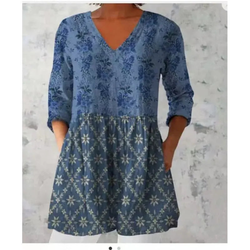 A woman wearing a vibrant printed loose-fitting dress with a wide waist and 3/4 length sleeves.