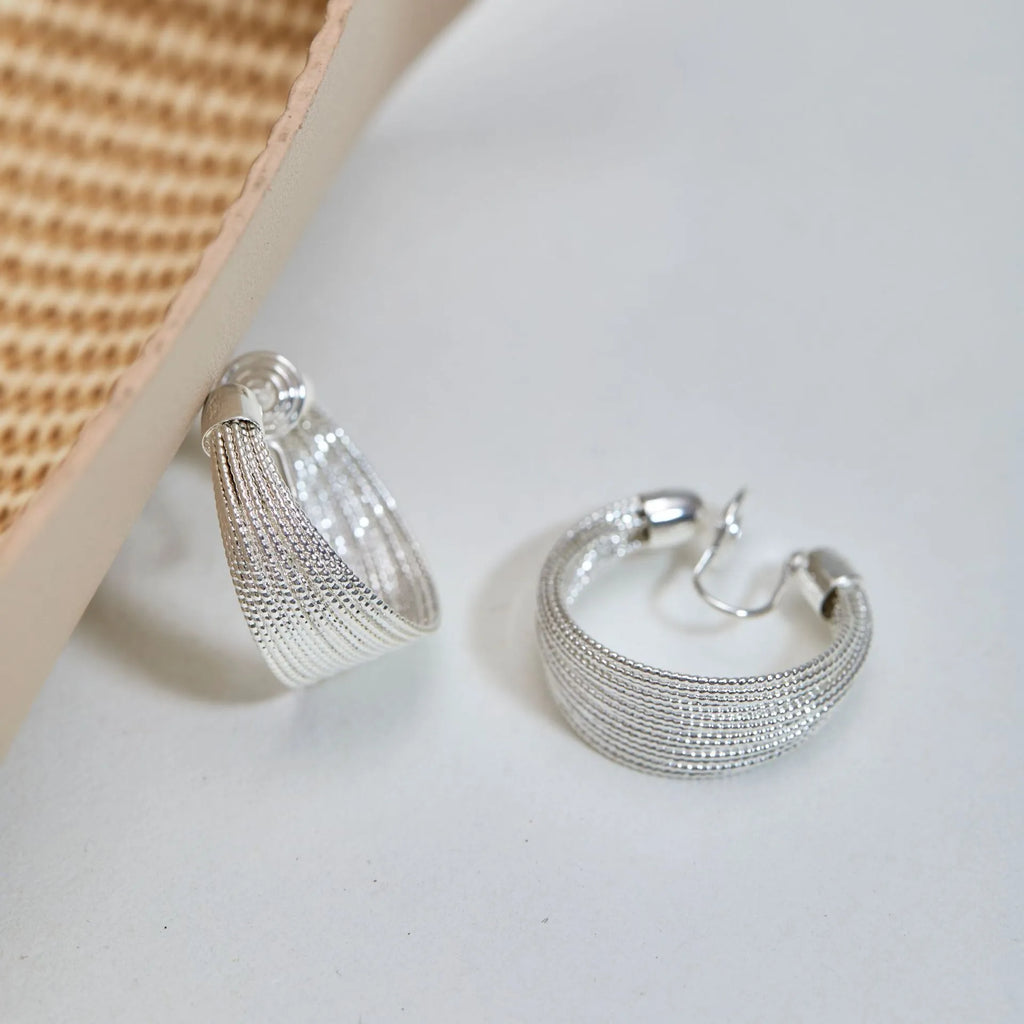 Geometric multi-layer copper earrings with an electroplated silver or gold finish, shown as studs and clips.